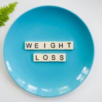 A blue plate with 'weight loss' tiles and a fern leaf on white background.