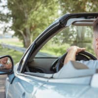 man driving shiny car on road