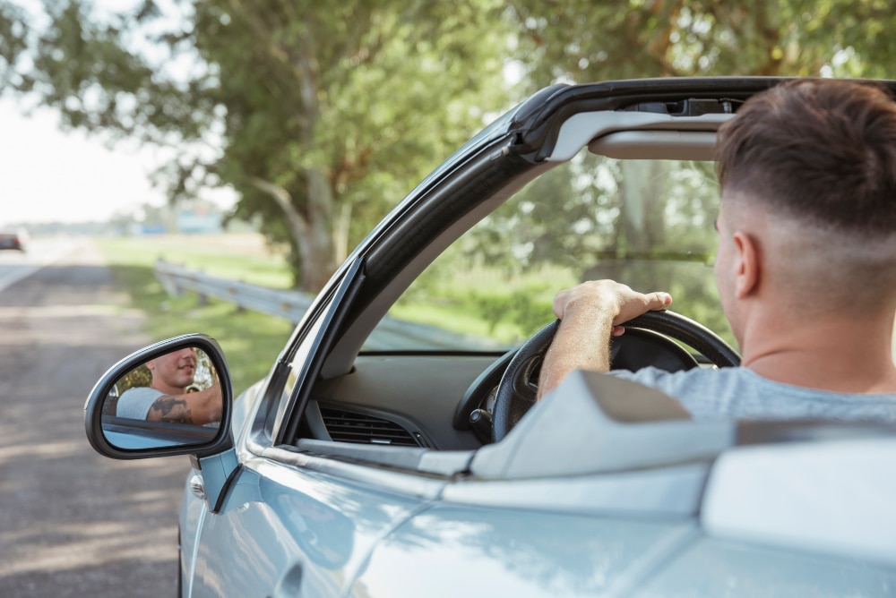 man driving shiny car on road