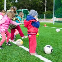 Kids having fun playing soccer outdoors on a sunny day in a park.