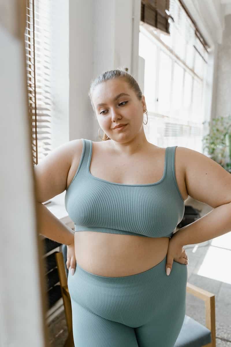 Plus size woman embracing body positivity in stylish activewear, indoors.
