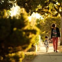 woman holding a child walking in the pathway