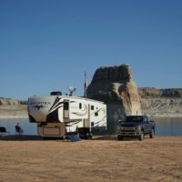 A serene RV camping scene by Lake Powell with stunning rock formations, perfect for a travel adventure.