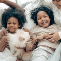 Happy family bonding time with kids and a Pomeranian dog in cozy home setting.