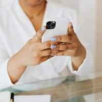 Close-up of a person holding a smartphone indoors with a focus on manicured nails.
