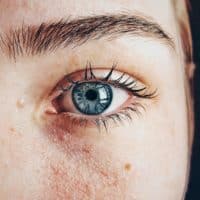 Detailed close-up of a woman's blue eye showcasing natural skin texture and eyebrow.