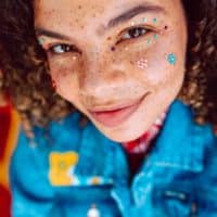 Vibrant portrait featuring a young person with creative face makeup, exuding youthful joy and style.