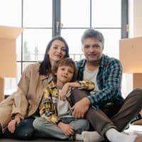 Happy family sitting together in their new home surrounded by moving boxes.
