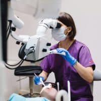 dentist in purple scrubs attends to patient