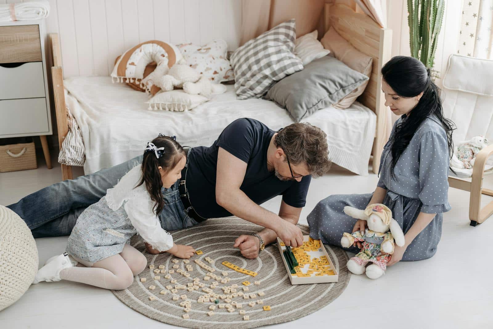 A family enjoying a bonding moment playing Scrabble together in a cozy bedroom setting.