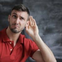 Man in Red Polo Shirt Sitting Near Chalkboard