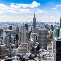 A stunning aerial view of New York City's skyline featuring the iconic Empire State Building under a bright blue sky.