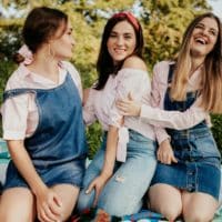Group of women sitting on blankets enjoying a sunny picnic outdoors.
