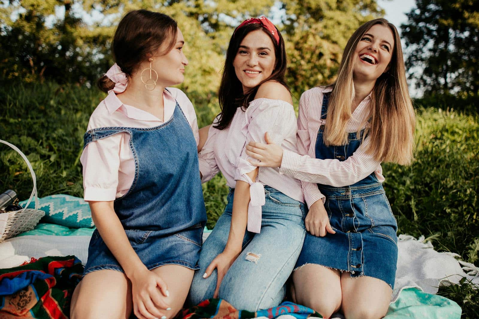 Group of women sitting on blankets enjoying a sunny picnic outdoors.